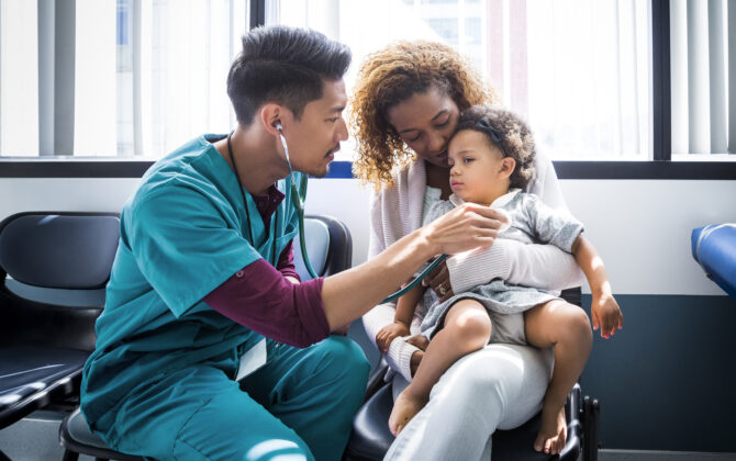 Male nurse examining baby girl with stethoscope in hospital